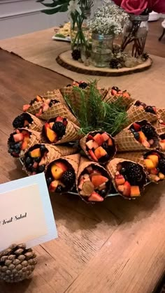 a table topped with lots of cones covered in fruit and veggies next to a card