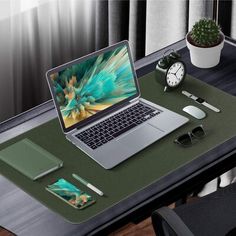 an open laptop computer sitting on top of a wooden desk next to a clock and plant