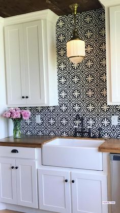 a white kitchen with black and white tile on the backsplash, wooden counter tops and cabinets