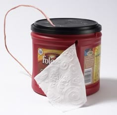 a red coffee can with a white napkin sticking out of it's lid and the caption reads, 8 repurpose a coffee can to hold and protect tp