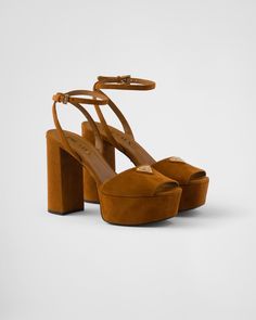 The iconic geometric shape of the triangle logo embellishes these suede sandals with sophisticated charm. The contemporary high-heeled platform silhouette is completed with refined ankle straps. Prada Platform Heels, Re Edition Prada, Cognac Sandals, Metal Lettering, Latest Sandal, Ballerina Slippers, Mens Travel Bag, Leather Heels Sandals, Leather Platform Sandals