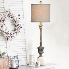 a table with a lamp on top of it next to a wreath and other items