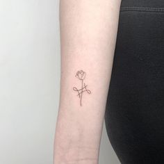 a woman's arm with a small cross and flower tattoo on the left wrist