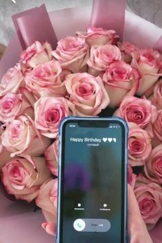 a person holding a cell phone in front of a bouquet of roses with the text happy birthday on it