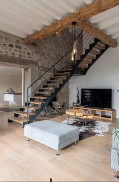 a living room with stone walls and wooden flooring, stairs leading up to the second floor