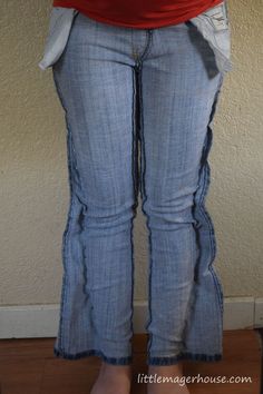 a woman is standing in front of a wall with her hands on her hips and wearing jeans