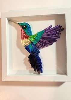 a colorful bird in a white frame hanging on the wall with its wings spread out