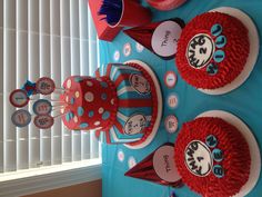 a table topped with red and blue cakes next to cupcakes on top of each other