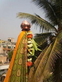 there is a large metal pot on top of a pole with flowers and leaves around it