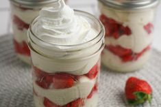 two mason jars filled with whipped cream and strawberries