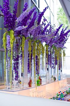 purple and yellow flowers are in glass vases