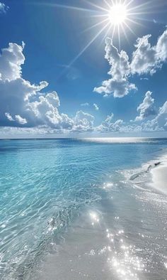 the sun shines brightly over an ocean beach with white sand and clear blue water