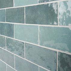 a blue brick wall with white grouting on the top and bottom tiles in different colors