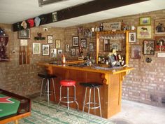 a bar with three stools and pictures on the wall