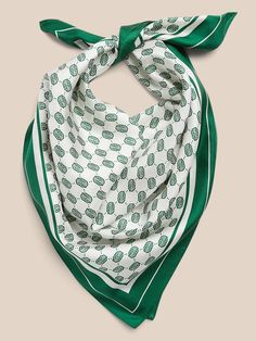 a green and white scarf with cactus print on the bottom, in front of a beige background