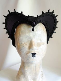 This is a purple and black version of one of most successful designs called Countess. This vampire style headdress is covered with dark purple taffeta and embellished with black cord trimming all around the edges.It is further trimmed with black crystal details that create a halo effect as well as small l beads that were hand-sewn on the trimming to create rich textural interest. The piece is completed with a black crystal handmade element placed at the center front for all that extra drama that Black Gothic Festival Costume, Witchy Black Costume Hats For Cosplay, Fitted Black Gothic Costume, Black Fitted Gothic Costume, Elegant Halloween Theater Costumes, Gothic Headpieces For Cosplay Events, Black Fantasy Costume Accessories For Theater, Black Punk Costume Hats And Headpieces, Halloween Cosplay Costume Accessories With Tall Crown