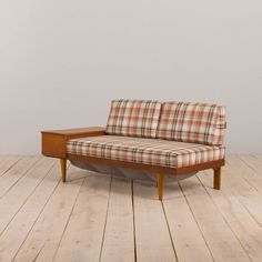 a plaid couch sitting on top of a wooden floor next to a whiteboard wall