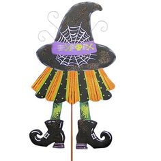 a halloween decoration with a witch hat and boots on it's head, sitting on top of a stick