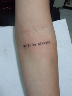 a person with a tattoo that says we'll be alright on their left arm