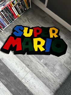 there is a rug that says super mario on the floor in front of a bookcase