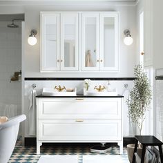 a bathroom with two sinks, cabinets and a bathtub