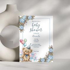 a baby shower with a teddy bear and balloons in the corner next to a vase