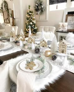 a dining room table decorated for christmas with white and gold decorations