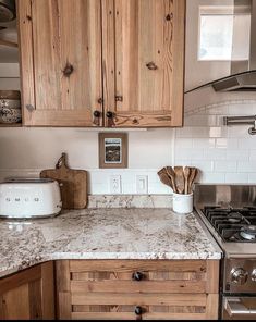 a kitchen with wooden cabinets and white marble counter tops, an oven and toaster