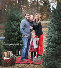 a family standing in front of christmas trees