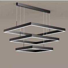 three rectangular lights suspended from the ceiling over a gray surface with black and white lines