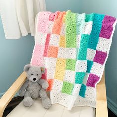 a crocheted blanket on a chair with a teddy bear sitting next to it