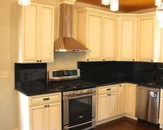 a kitchen with white cabinets and black counter tops, stainless steel appliances and wood flooring