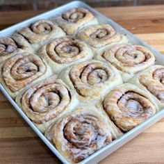 a pan filled with cinnamon rolls sitting on top of a wooden table