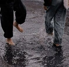 two people are walking in the rain with their feet up and one person is holding an umbrella