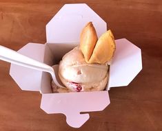 an ice cream sundae in a paper box with two scoops on the side