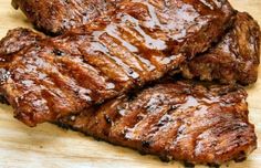 several pieces of meat sitting on top of a wooden cutting board