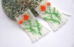 Handmade beaded fringe flowers earrings with sterling silver waves in white, green, yellow and orange colors. These earrings are fully handcrafted. They are hand woven with czech glass beads and nylon thread. The top part is hand-formed from sterling silver wire, hammered and gently polished. The ear wires are made from silver wire, formed and polished as well. Seed bead colors: two shades of green, lemon yellow, pumpkin orange on a half-transparent white background. The full length is 2.6" (6.5 cm). The drop length is 2.2" (5.5 cm). This item is in stock so it can be shipped within a couple of days. Beautiful cottagecore and spring earrings for the girl who loves floral jewelry. Handmade Green Beaded Earrings For Spring, Handmade White Beaded Earrings For Spring, Bohemian White Beaded Earrings For Spring, Beaded Flower Earrings, Yellow Pumpkin, Handwoven Earrings, Green Lemon, Flowers Earrings, Spring Earrings