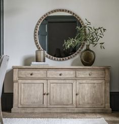 a dresser with a mirror on it and a plant in the corner next to it