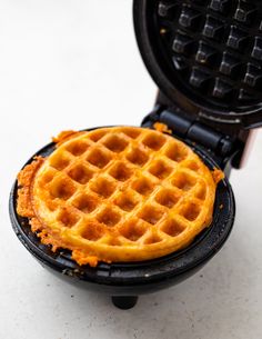 a waffle is sitting on top of a small black plate with orange sauce in it