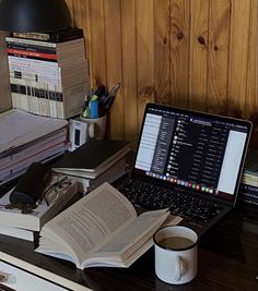 an open laptop computer sitting on top of a desk next to a stack of books