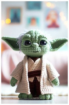 a crocheted yoda doll is posed on a table