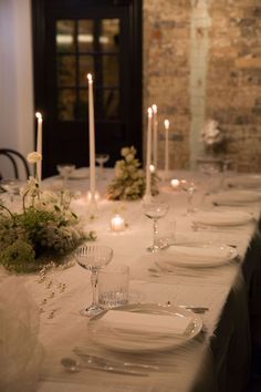 the table is set with white plates and silverware, candles, and flowers on it