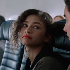 a woman sitting in an airplane looking at another person