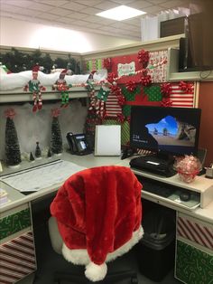 an office cubicle decorated for christmas with santa's hat on the desk and computer