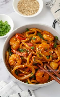 a bowl filled with shrimp and vegetables next to chopsticks on top of a table