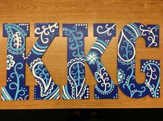 the letters are made out of wood and decorated with blue paisley designs, including the letter kkjg