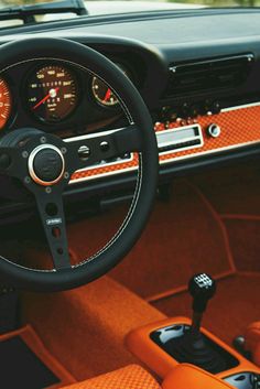 the interior of an old car with orange leather seats and gauges on the dashboard