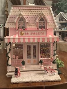 a pink and white doll house on top of a wooden table