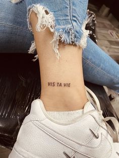 a woman's foot with the words vis ta vie tattooed on her left ankle