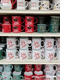 many different colored coffee mugs are on the shelves in a store with white and red lettering